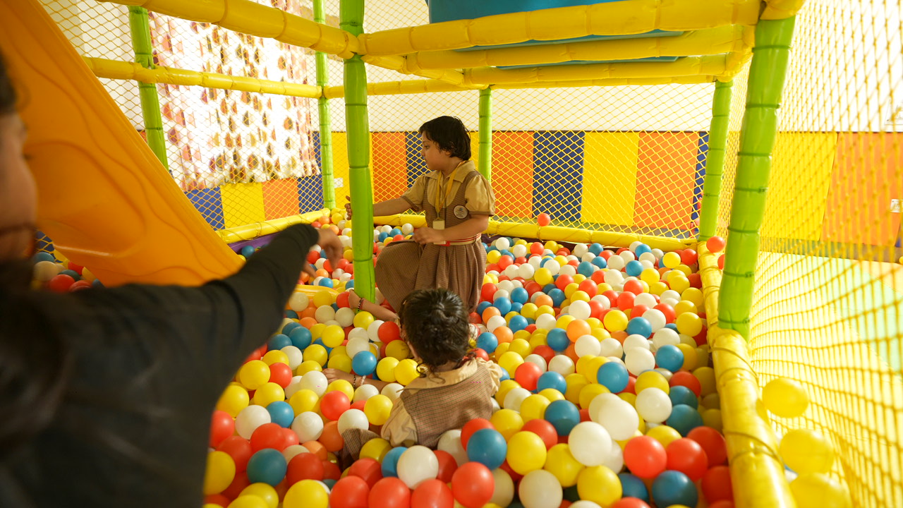 A teacher guiding students playing in the ball pit at SKS World School