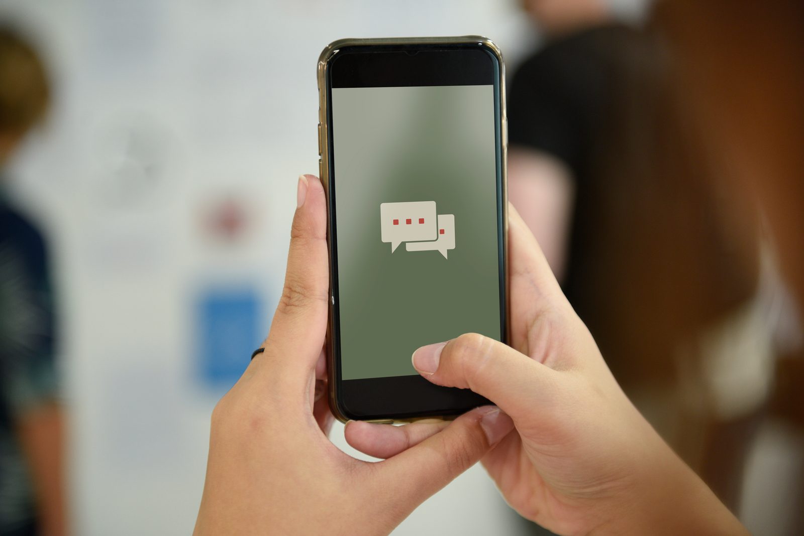 A parent's hands holding a phone showing a messaging app