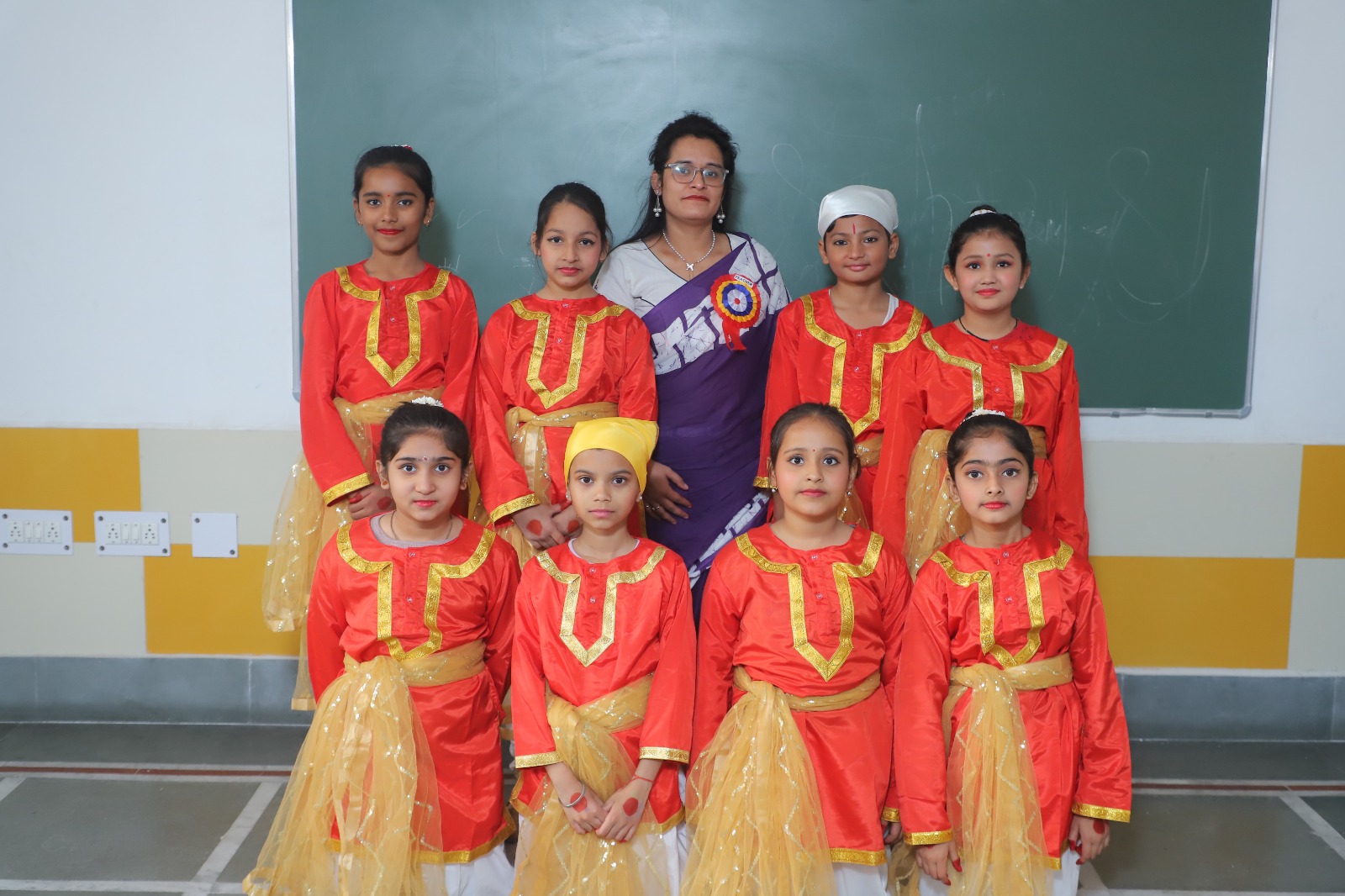 A teacher with a group of SKS World School students in front of the classroom board